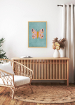 Aranżacja wnętrza, na ścianie wisi plakat w ramce: pastelowy motyl różowy na niebieskim tle skandynawski do pokoju dziecięcego
