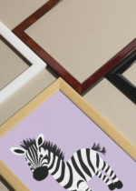 Widok z góry na cztery drewniane ramki, w jednej z nich oprawiony plakat do pokoju dziecięcego zebra na pastelowym lawendowym tle