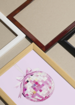 Widok z góry na cztery drewniane ramki, w jednej z nich oprawiony plakat różowa kula disco mozaika glamour do pokoju dziecięcego
