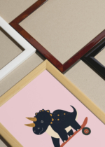 Widok z góry na cztery drewniane ramki, w jednej z nich oprawiony plakat do pokoju dziecięcego dinozaur triceratops na deskorolce