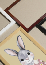 Widok z góry na cztery drewniane ramki, w jednej z nich oprawiony plakat królik w kwiecistej sukience w stylu ilustracyjnym do pokoju dziecięcego