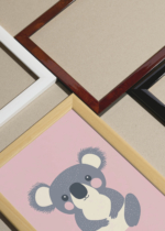 Widok z góry na cztery drewniane ramki, w jednej z nich oprawiony plakat koala na różowym tle do pokoju dziecięcego