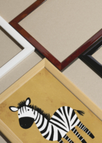 Widok z góry na cztery drewniane ramki, w jednej z nich oprawiony plakat do pokoju dziecięcego zebra safari na pomarańczowym tle