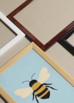 Widok z góry na cztery drewniane ramki, w jednej z nich oprawiony plakat minimalistyczna pszczółka do pokoju dziecięcego