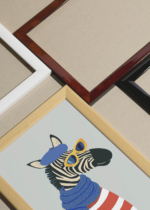 Widok z góry na cztery drewniane ramki, w jednej z nich oprawiony plakat do pokoju dziecięcego zebra w berecie i okularach w stylu paryskim