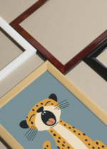 Widok z góry na cztery drewniane ramki, w jednej z nich oprawiony plakat minimalistyczny gepard na błękitnym tle do pokoju dziecięcego