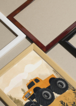 Widok z góry na cztery drewniane ramki, w jednej z nich oprawiony plakat monster truck pomarańczowy samochód do pokoju dziecięcego
