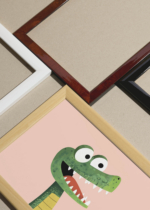 Widok z góry na cztery drewniane ramki, w jednej z nich oprawiony plakat sympatyczny dinozaur T-Rex do pokoju dziecięcego