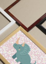Widok z góry na cztery drewniane ramki, w jednej z nich oprawiony plakat dinozaur triceratops retro do pokoju dziecięcego