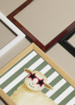 Widok z góry na cztery drewniane ramki, w jednej z nich oprawiony plakat do pokoju dziecięcego owieczka w różowych okularach
