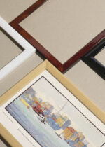 Widok z góry na cztery drewniane ramki, w jednej z nich oprawiony plakat Nowy Jork z promu akwarela Rachael Robinson Elmer