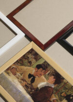 Widok z góry na cztery drewniane ramki, w jednej z nich oprawiony plakat Édouard Manet Chez le Père Lathuille