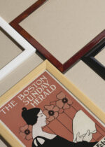 Widok z góry na cztery drewniane ramki, w jednej z nich oprawiony plakat The Boston Sunday Herald Ethel Reed 1895 secesja