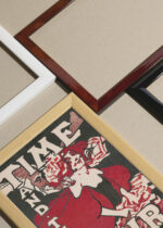 Widok z góry na cztery drewniane ramki, w jednej z nich oprawiony plakat Ethel Reed Time and The Hour kobieta czerwone włosy