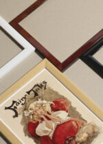 Widok z góry na cztery drewniane ramki, w jednej z nich oprawiony plakat vintage dziewczyna w czerwonej sukni Ethel Reed