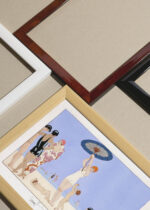 Widok z góry na cztery drewniane ramki, w jednej z nich oprawiony plakat au Lido plaża Art Deco George Barbier 1919