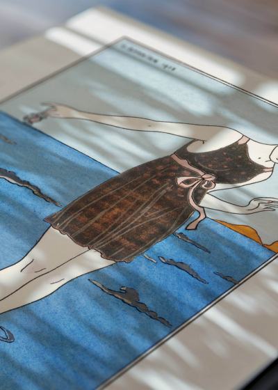 Widok z góry na cztery drewniane ramki, w jednej z nich oprawiony plakat Art Deco kobieta na plaży George Barbier 1913