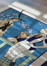 Widok z góry na cztery drewniane ramki, w jednej z nich oprawiony plakat Rugby Costume tailleur George Barbier Art Deco