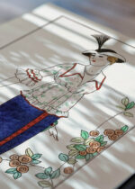 Widok z góry na cztery drewniane ramki, w jednej z nich oprawiony plakat Letnia moda 1912 George Barbier Art Deco