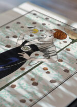 Widok z góry na cztery drewniane ramki, w jednej z nich oprawiony plakat Art Deco czarna suknia wieczorowa George Barbier