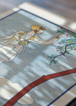 Widok z góry na cztery drewniane ramki, w jednej z nich oprawiony plakat La Saison des Prunes Mirabelles George Barbier