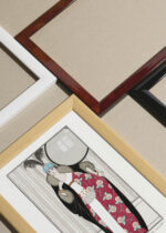 Zbliżenie na detale plakatu oprawionego w drewnianą białą ramkę od Plakatello®: moda 1912 George Barbier Art Deco czerwona suknia