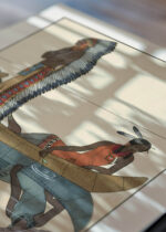 Widok z góry na cztery drewniane ramki, w jednej z nich oprawiony plakat Le long du Missouri George Barbier art deco