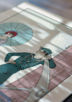 Widok z góry na cztery drewniane ramki, w jednej z nich oprawiony plakat Romance sans paroles Kobieta z Marynarzem George Barbier art déco