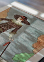 Widok z góry na cztery drewniane ramki, w jednej z nich oprawiony plakat La Promeneuse Mélancolique George Barbier 1922