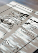 Widok z góry na cztery drewniane ramki, w jednej z nich oprawiony plakat czarno-biały Art Deco dama z lunetą 1914 George Barbier