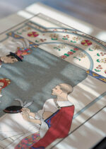 Widok z góry na cztery drewniane ramki, w jednej z nich oprawiony plakat George Barbier Entre deux feux Art Deco 1922