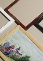 Widok z góry na cztery drewniane ramki, w jednej z nich oprawiony plakat Wille w Villers-sur-Mer Gustave Caillebotte