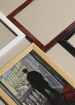 Widok z góry na cztery drewniane ramki, w jednej z nich oprawiony plakat Młody człowiek przy oknie Gustave Caillebotte 1876