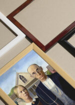 Widok z góry na cztery drewniane ramki, w jednej z nich oprawiony plakat American Gothic Grant Wood słynny obraz USA