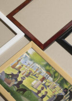 Widok z góry na cztery drewniane ramki, w jednej z nich oprawiony plakat Niedzielne popołudnie na wyspie Grande Jatte Seurat