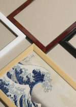 Widok z góry na cztery drewniane ramki, w jednej z nich oprawiony plakat Wielka Fala w Kanagawie Katsushika Hokusai