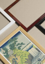 Widok z góry na cztery drewniane ramki, w jednej z nich oprawiony plakat wodospad Hokusai widoki góry Fuji japońskie ukiyo-e