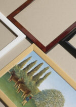 Widok z góry na cztery drewniane ramki, w jednej z nich oprawiony plakat Łąka Henri Rousseau pejzaż wiejski z bydłem i pasterzem