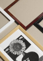 Widok z góry na cztery drewniane ramki, w jednej z nich oprawiony plakat słonecznik w wazonie Samuel Jessurun de Mesquita