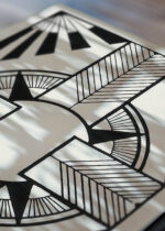 Zbliżenie na detale plakatu: geometryczny czarno-biały krzyż z promieniami S.J. de Mesquita