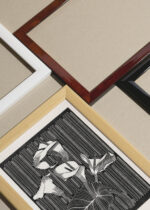 Widok z góry na cztery drewniane ramki, w jednej z nich oprawiony plakat czarno-biały drzeworyt kwiaty Kalie Mesquita vintage