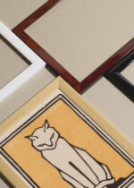 Widok z góry na cztery drewniane ramki, w jednej z nich oprawiony plakat minimalistyczny Kot Julie de Graag 1916 secesja vintage