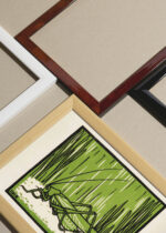 Widok z góry na cztery drewniane ramki, w jednej z nich oprawiony plakat konik polny Julie de Graag 1918 vintage grafika