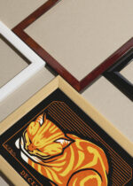 Widok z góry na cztery drewniane ramki, w jednej z nich oprawiony plakat śpiący kot Julie de Graag 1917 secesja vintage