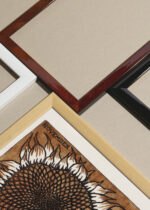 Widok z góry na cztery drewniane ramki, w jednej z nich oprawiony plakat słonecznik listopad Julie de Graag 1917 vintage