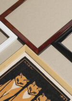 Widok z góry na cztery drewniane ramki, w jednej z nich oprawiony plakat trzy rude koty Julie de Graag 1916 vintage