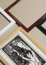 Widok z góry na cztery drewniane ramki, w jednej z nich oprawiony plakat Dwa raki czarno-biały Julie de Graag vintage