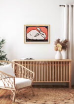 Aranżacja wnętrza, na ścianie wisi plakat w ramce: królik Julie de Graag 1916 czerwone tło vintage