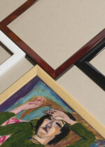 Widok z góry na cztery drewniane ramki, w jednej z nich oprawiony plakat Kobieta w zielonej marynarce Ernst Ludwig Kirchner