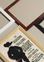 Widok z góry na cztery drewniane ramki, w jednej z nich oprawiony plakat Henri de Toulouse-Lautrec zapowiedź powieści Aristide Bruant